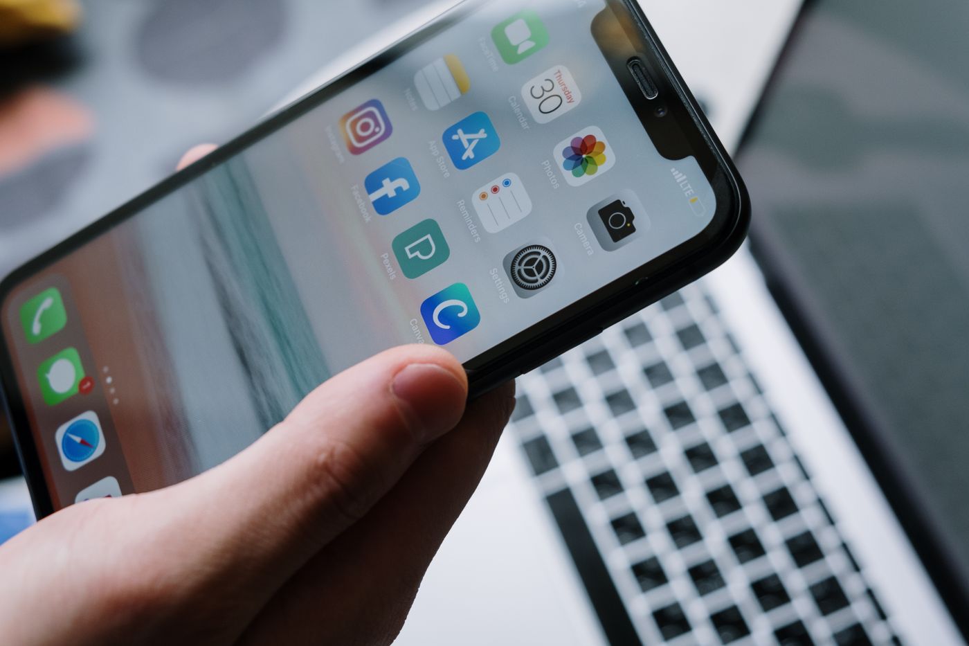 手揸住 iPhone,背後係 laptop